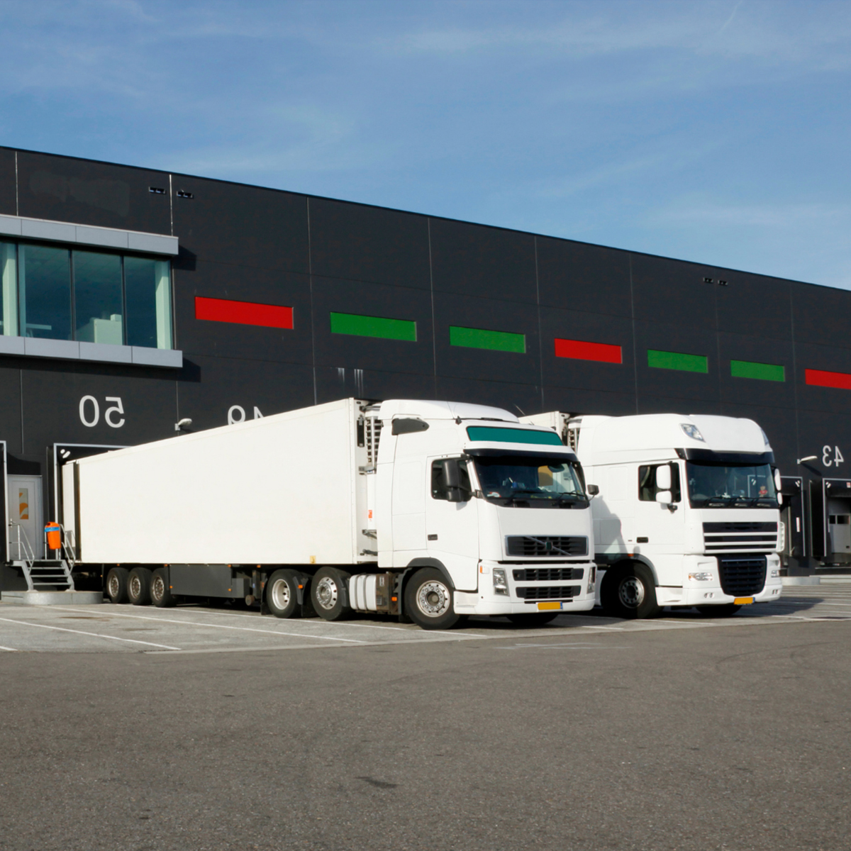 Deux camions sur un quai de chargement, illustrant les opérations de logistique et de transport.