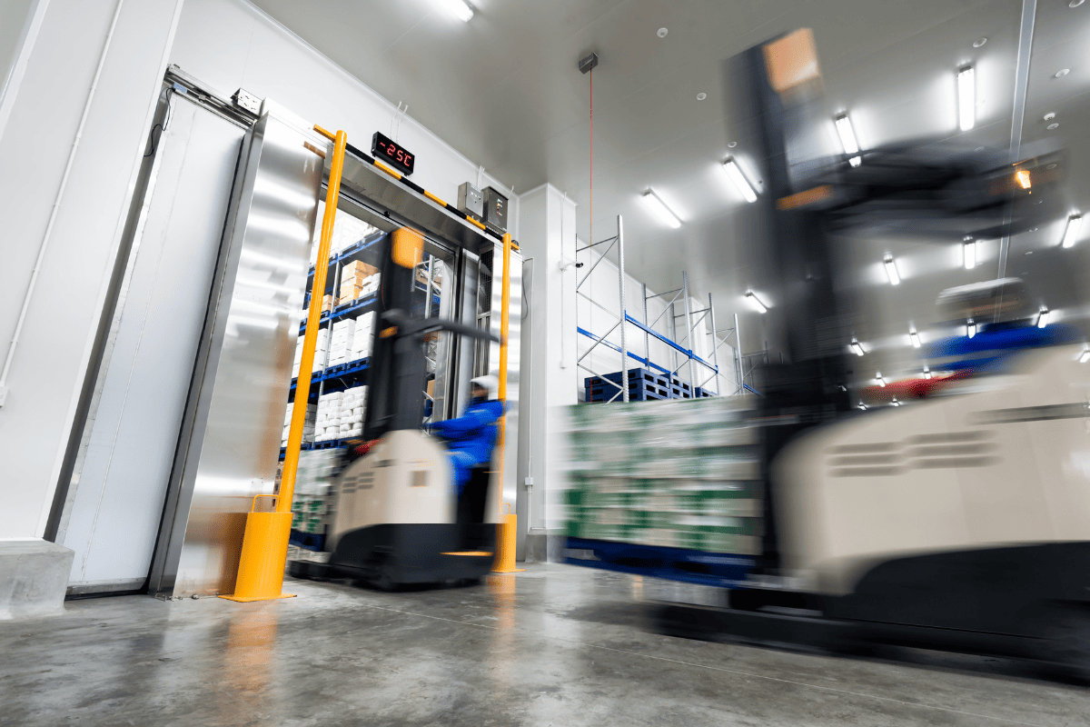 A forklift driver stores a pallet of foodstuffs in an industrial cold store